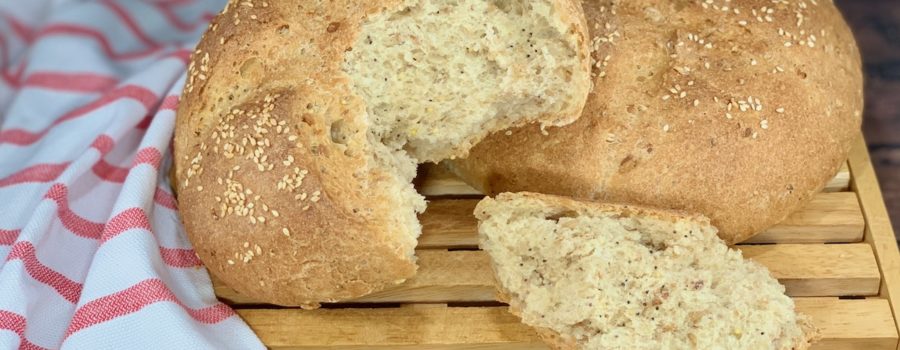 Closeup of Multigrain Sourdough Bread on cutting board with torn loaf and piece wide