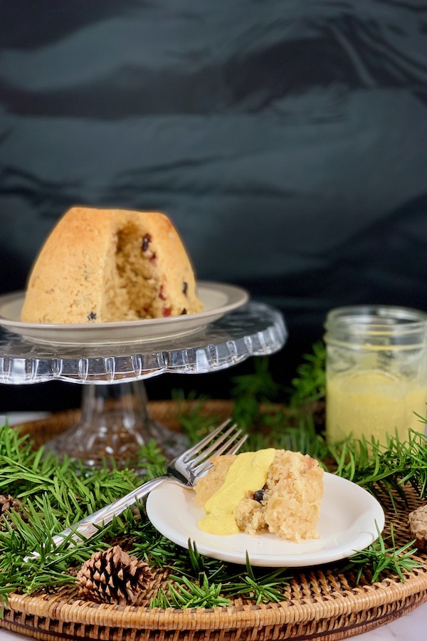 finished spotted dick steamed pudding with plated slice and vanilla sauce
