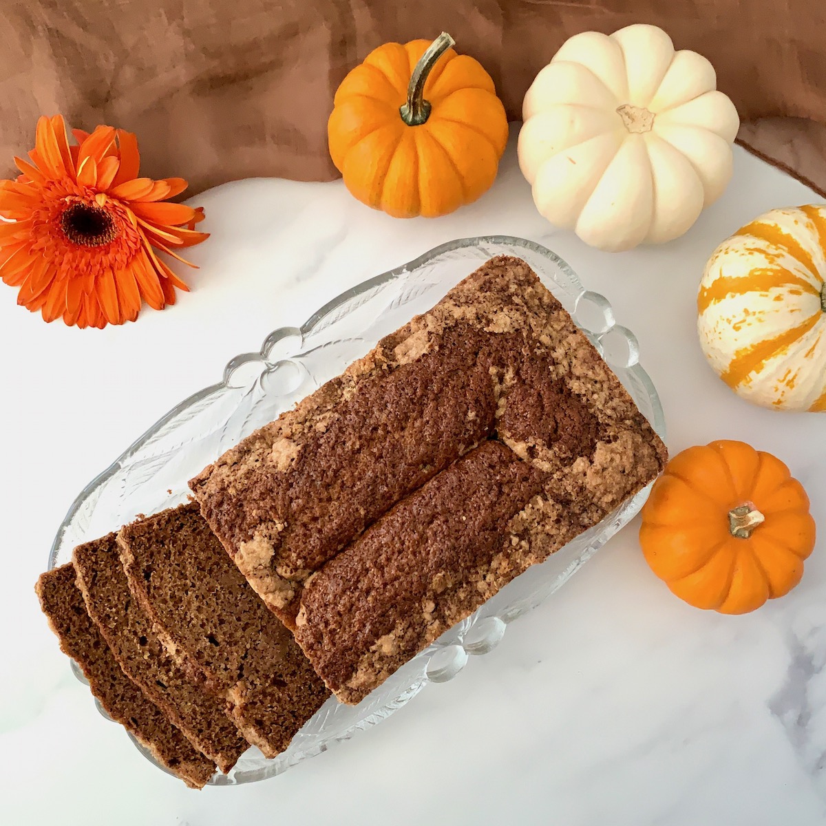 Sourdough Spice Cake sliced on plate with pumpkins overhead